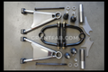A collection of metal control arms and spindle parts for a vehicle suspension system, including upper and lower arms, cross shaft, frame bracket, ball joints, and spindle cup, with the brand 'CANDO' visible on the top left.