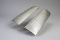 A pair of silver metal front corner fillers for a vehicle.