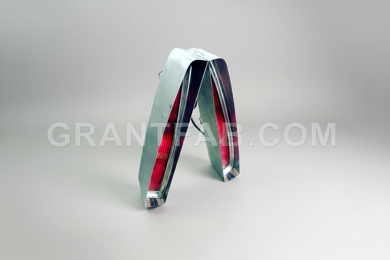 A pair of 94-99 Cadillac tail light buckets made from 20 gauge sheet metal, with a chrome finish and red tail lights visible.