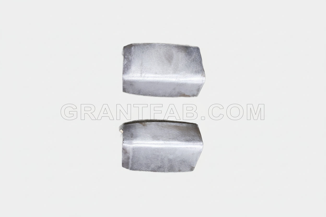 A pair of silver-colored sheet metal corner fillers for a Nissan Hardbody vehicle.