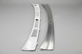 A silver-colored metal wiper cowl filler piece for a Toyota vehicle, displayed against a black background.